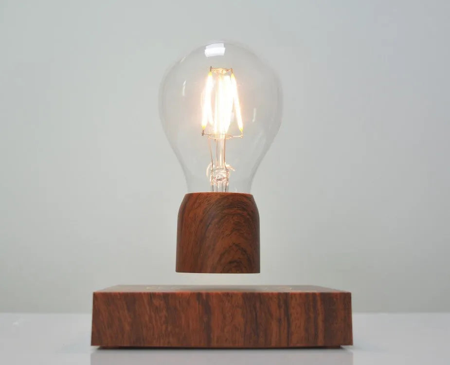 Magnetic levitating light bulb floating above an imitation wood base on a desk.