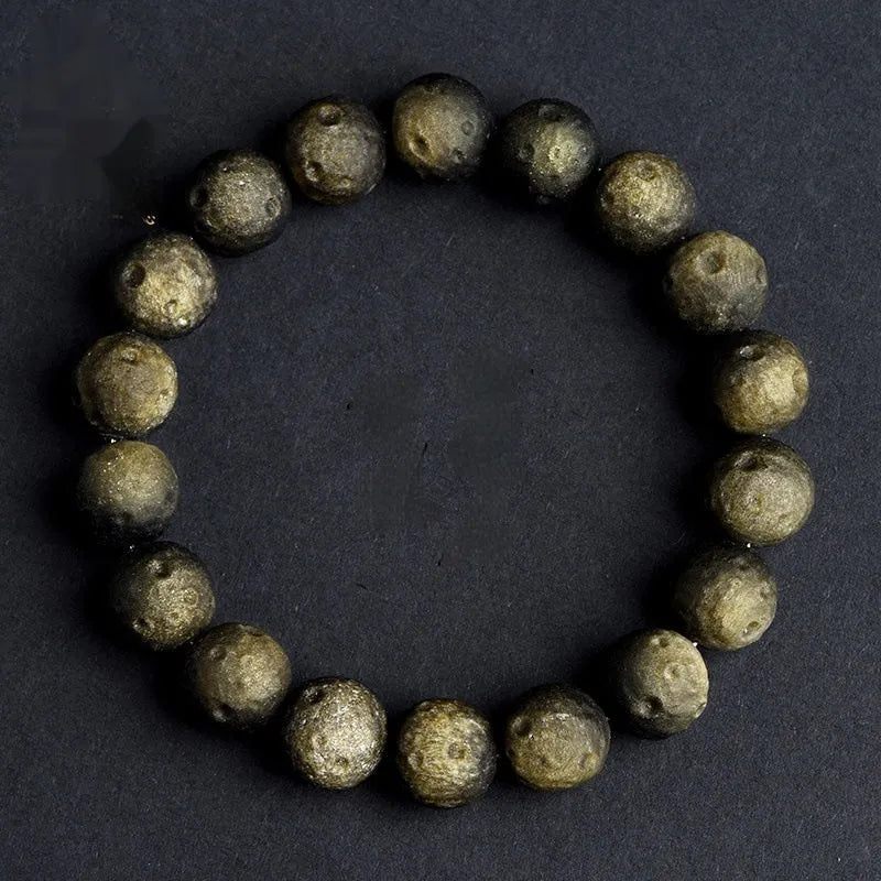 Natural obsidian crater ball bracelet with textured beads on a wrist, showing silver stone meteorite colour variant.