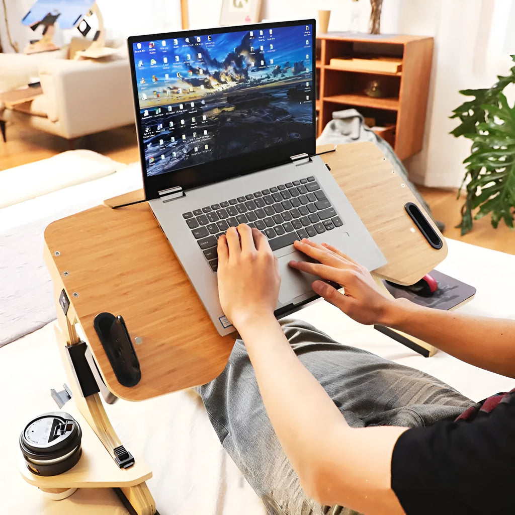 White wooden folding laptop table on a bed at an adjustable angle.