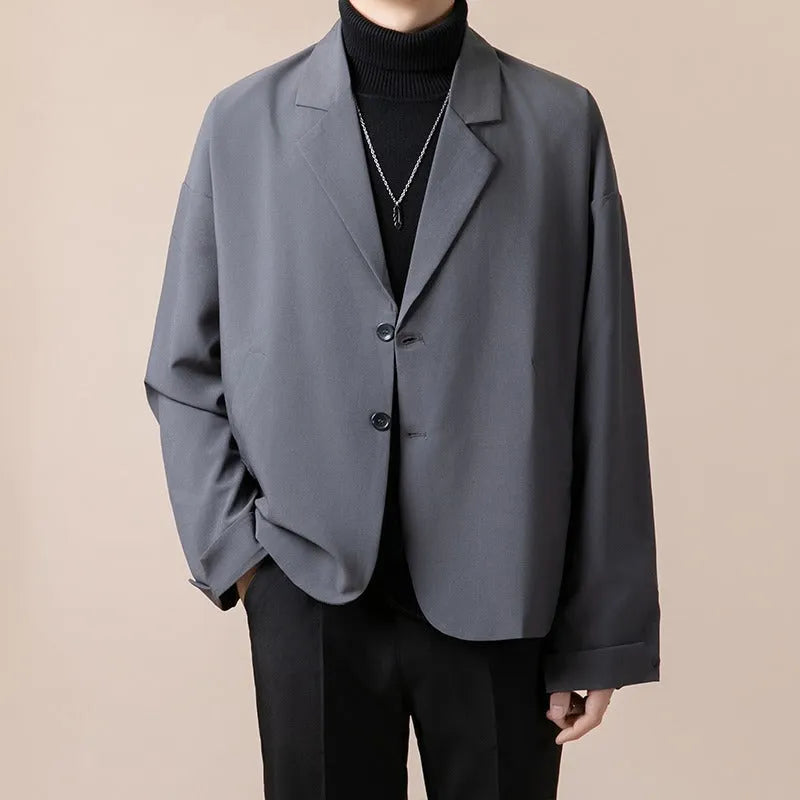 Man wearing a loose fit casual blazer in a light business style, available in black, grey, apricot and brown.