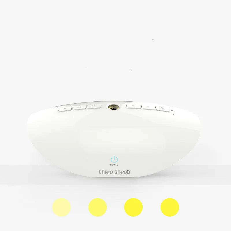White-coloured white noise sleep aid machine with mechanical control buttons on a bedside table.