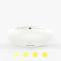 White-coloured white noise sleep aid machine with mechanical control buttons on a bedside table.