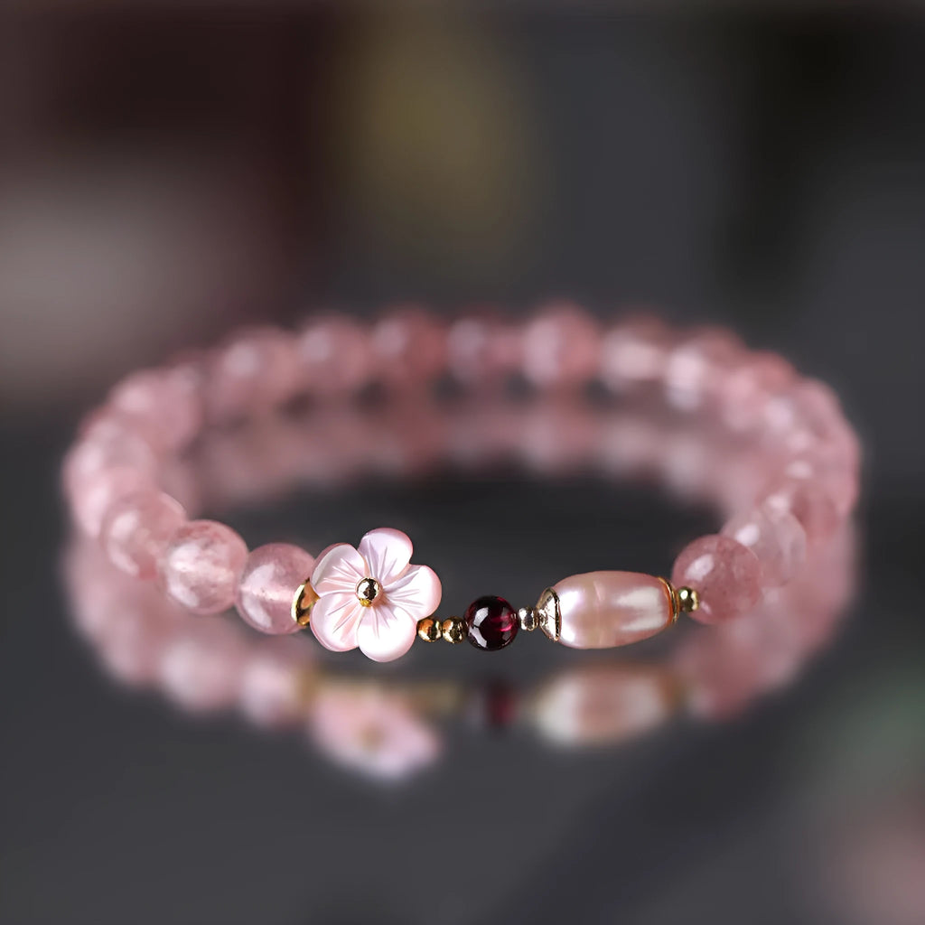 Strawberry quartz crystal bracelet with a peach blossom flower shape on a wrist.