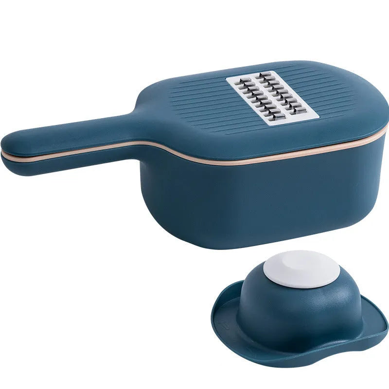 Dark blue vegetable cutter with four stainless steel blades, drain basket, and hand protection guard on kitchen counter