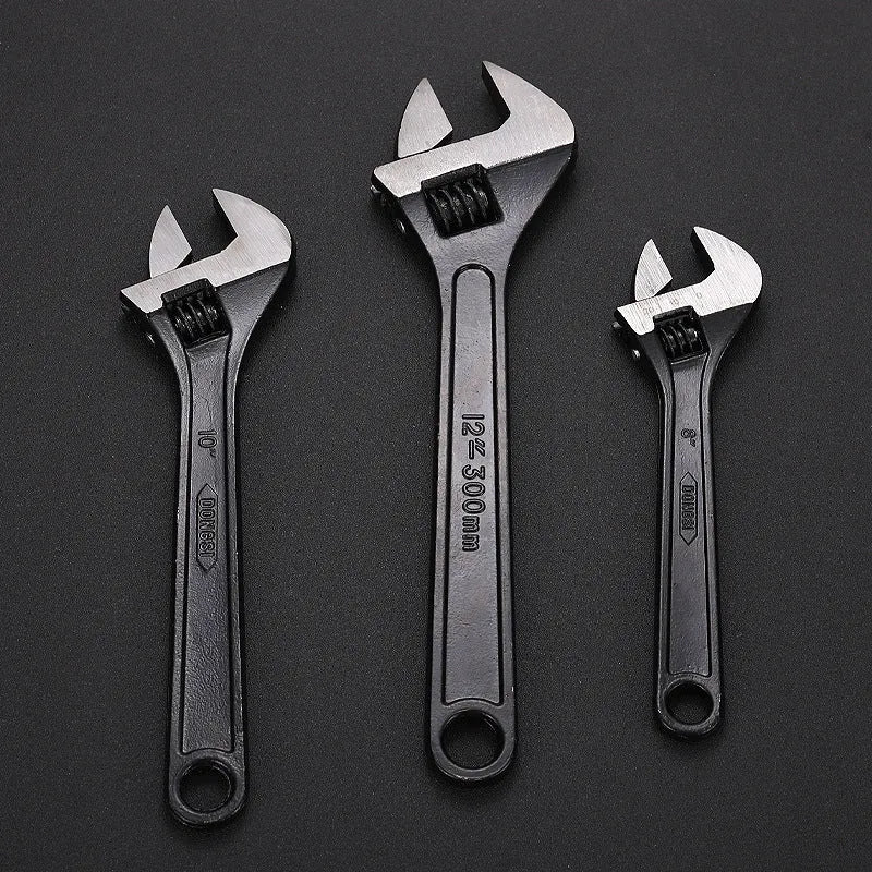 High carbon steel adjustable open-end wrench with black finish on a workbench.
