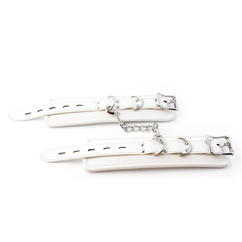 White PU foam bondage set showing handcuffs, ankle cuffs, and a neck scarf on a dark background.