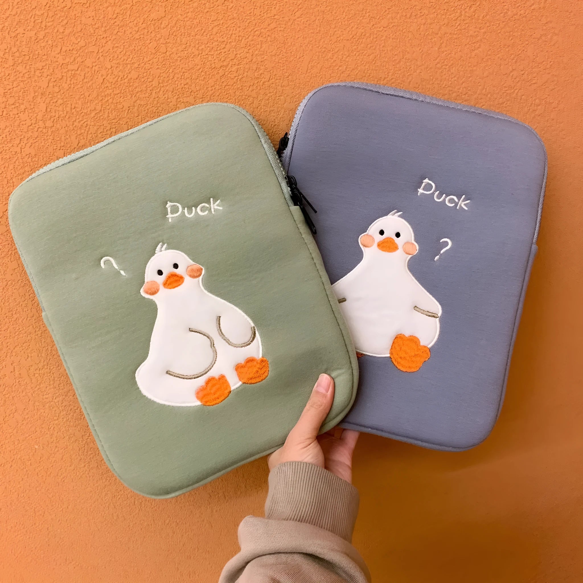 Blue cotton tablet case with embroidered cartoon duck design and a zip closure.
