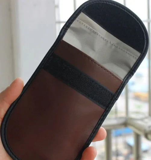 Black microfiber Faraday pouch for blocking car key and credit card signals, shown with a key fob inside.