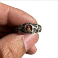 Close-up of a hand-forged copper ring with a textured Grotto Buddha and rock pattern.