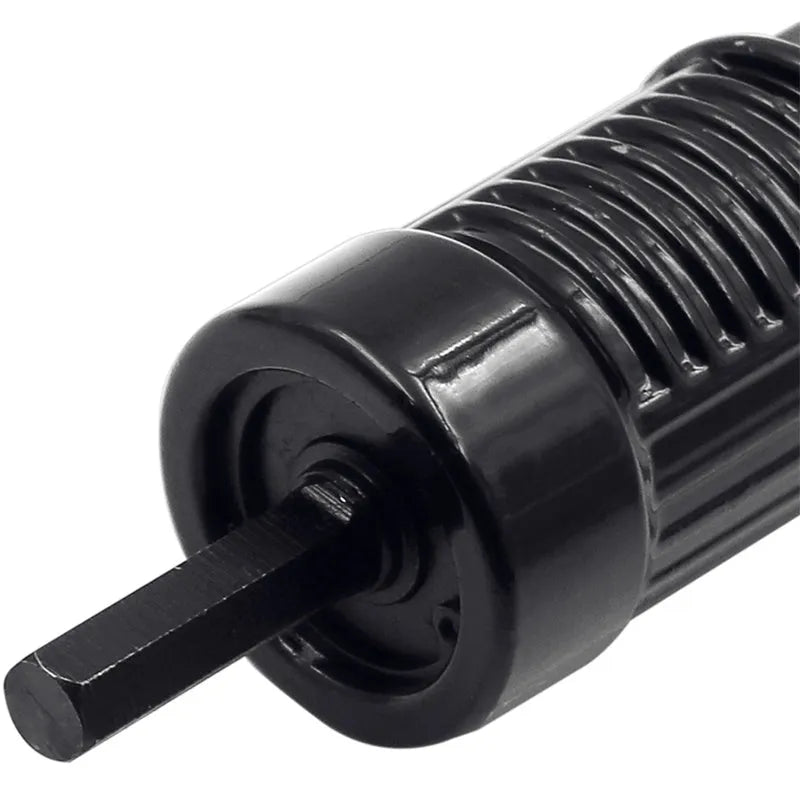 Black metal electric drill rivet gun with wrench and rivet heads on a workbench.