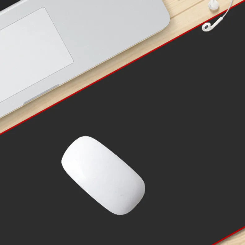 Long black desk mat with overlock stitching for keyboard and mouse on a wooden desk.