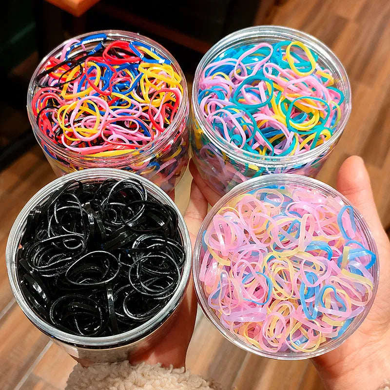 Pack of multicoloured thin TPU baby hair ties for toddlers in a reusable clear storage container.