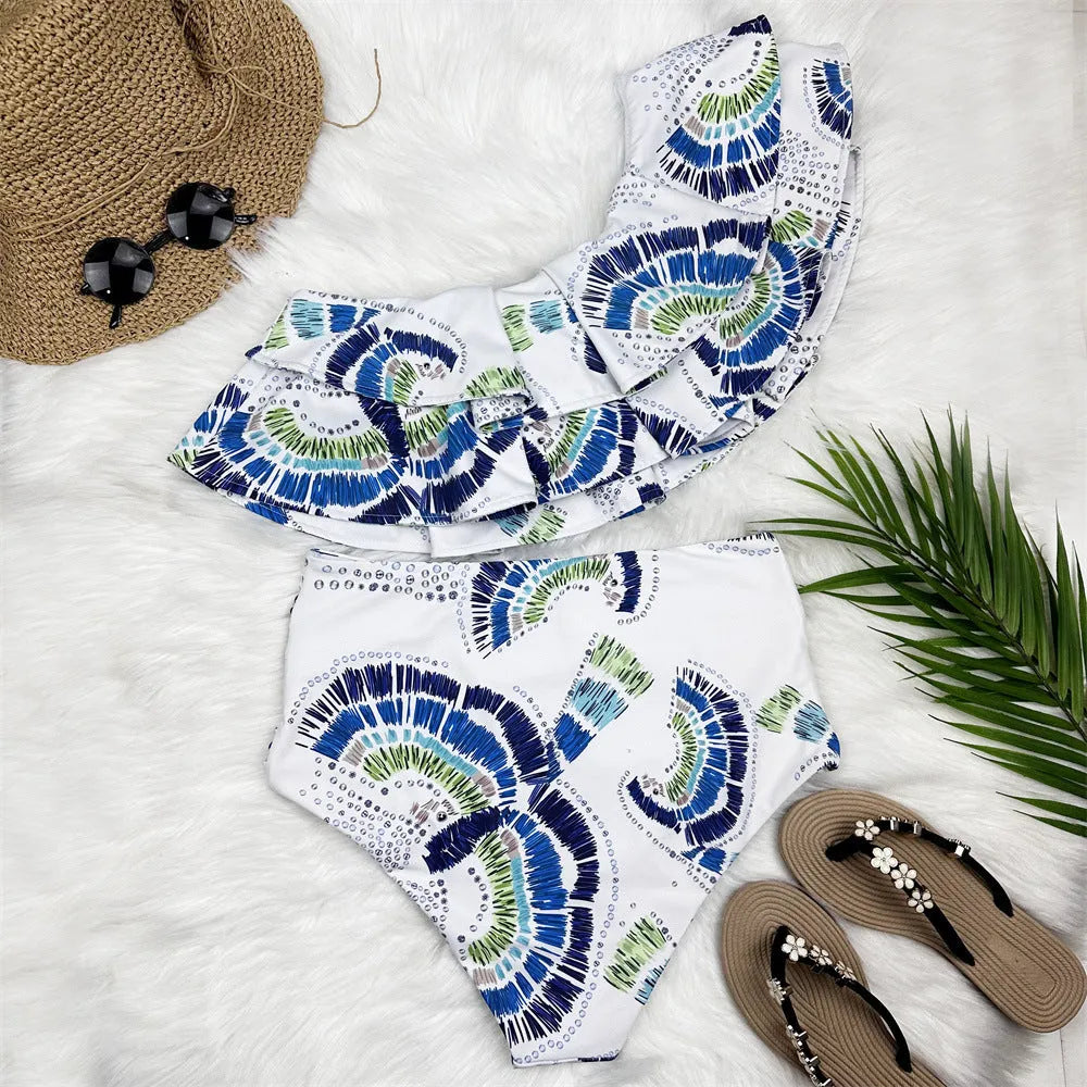 White women's one-shoulder swimsuit with a layered lotus leaf design skirt and high leg split.