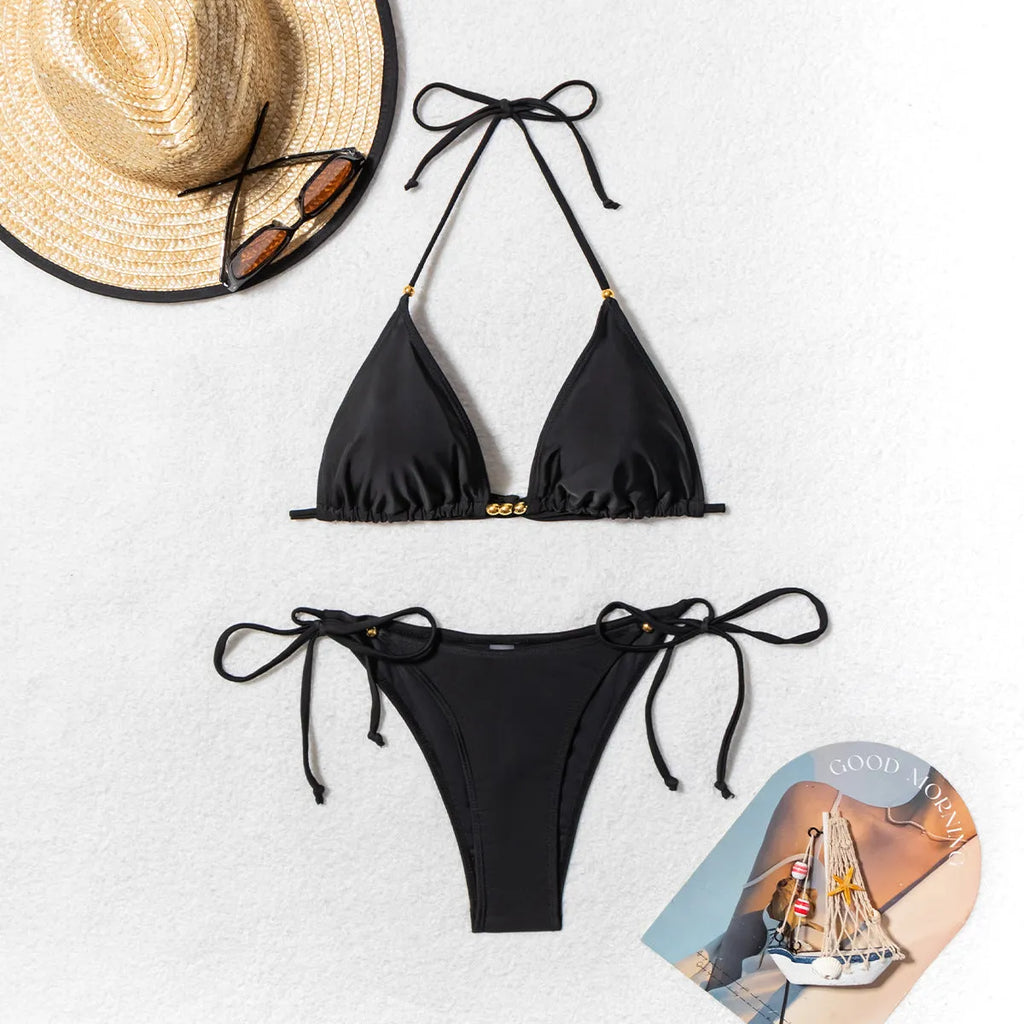 Black women's bikini swimsuit with metal bead decoration and a split design.