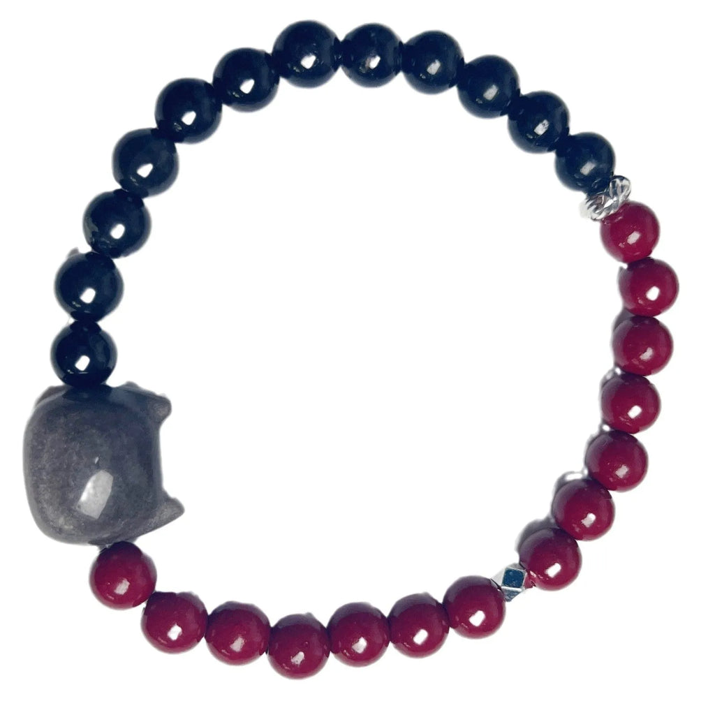 Close-up of handmade obsidian-colour bead bracelet with metal cat charm on adjustable red string.