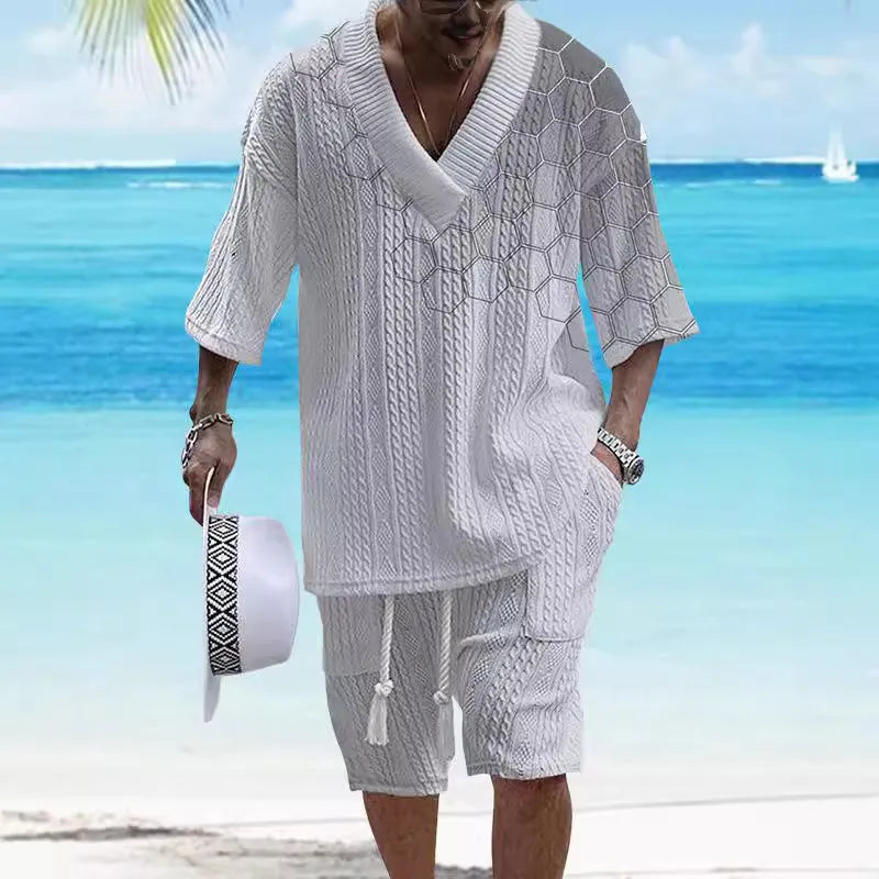 A man wearing a printed drop-shoulder knitted top and matching shorts from a casual two-piece loungewear set.
