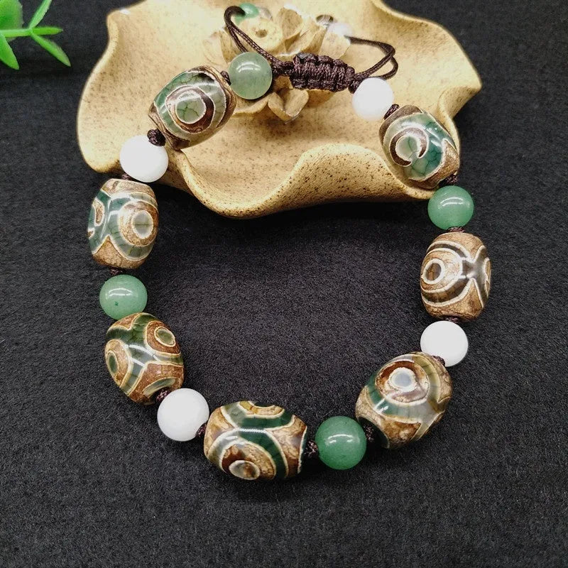 Green agate hand-woven Tibetan bracelet with three-eye geometric design on a wrist.