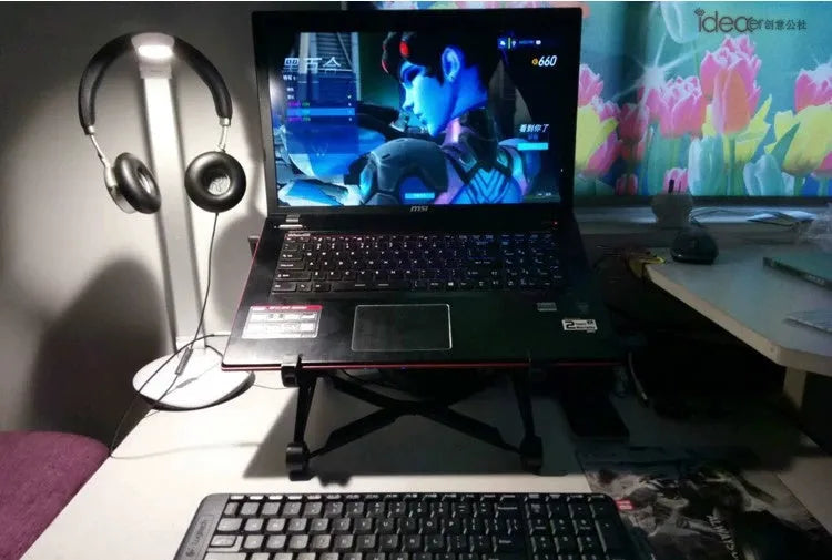 Black foldable portable laptop stand with lifting mechanism, shown with carrying case