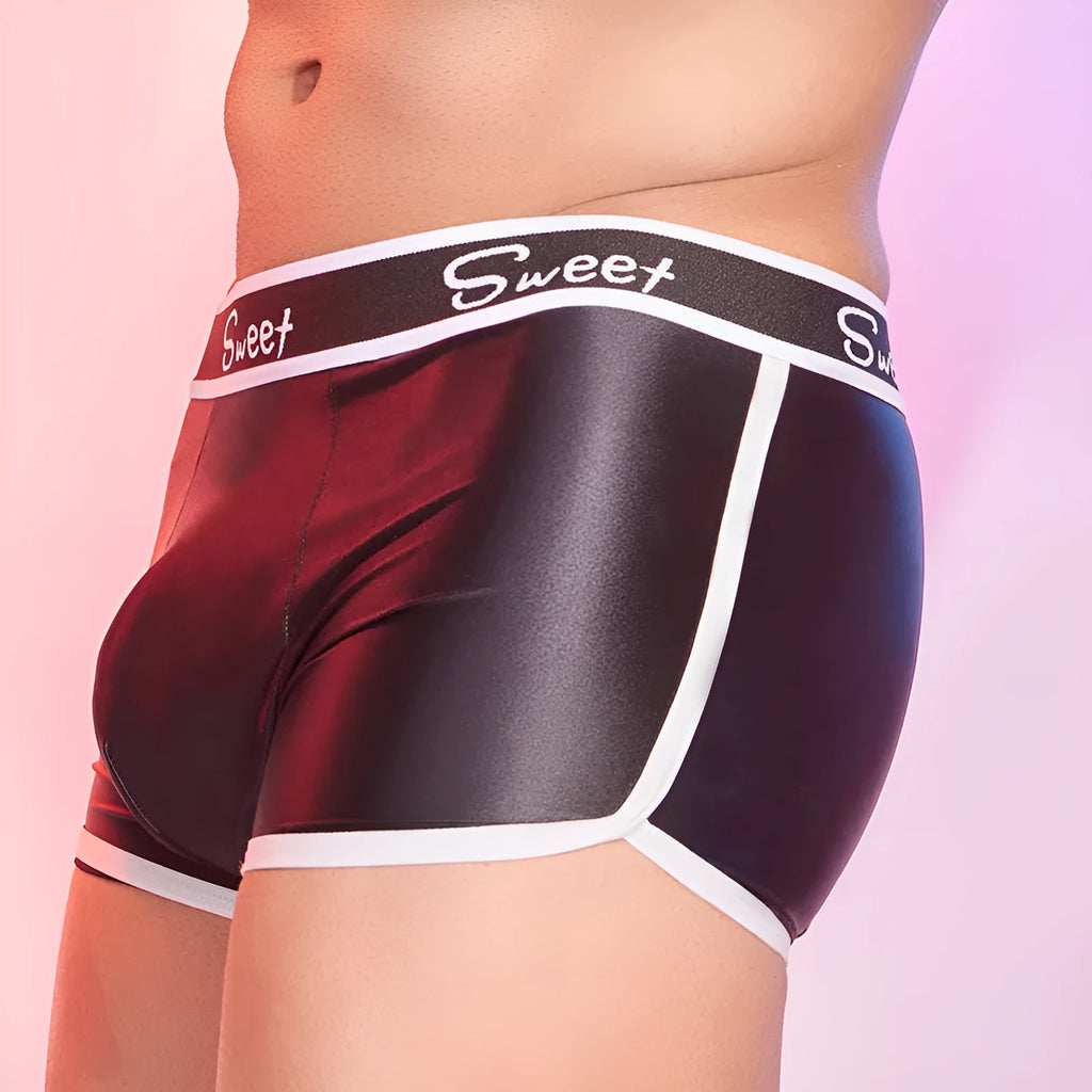 Men's shiny silky nylon boxer shorts in black, sapphire blue, and white colours on a grey background.