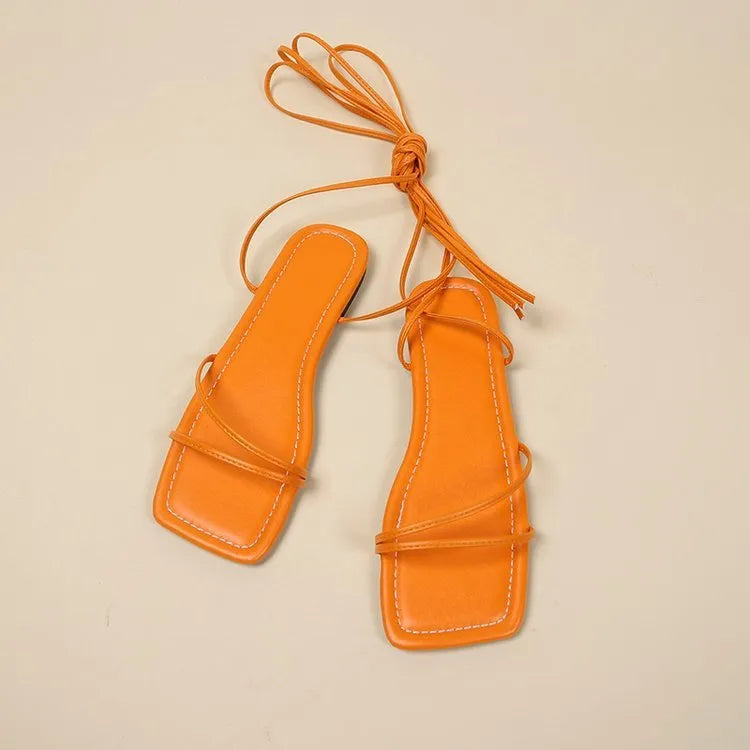 Women's flat sandals with ankle strap and front lace-up fastening in square toe design.
