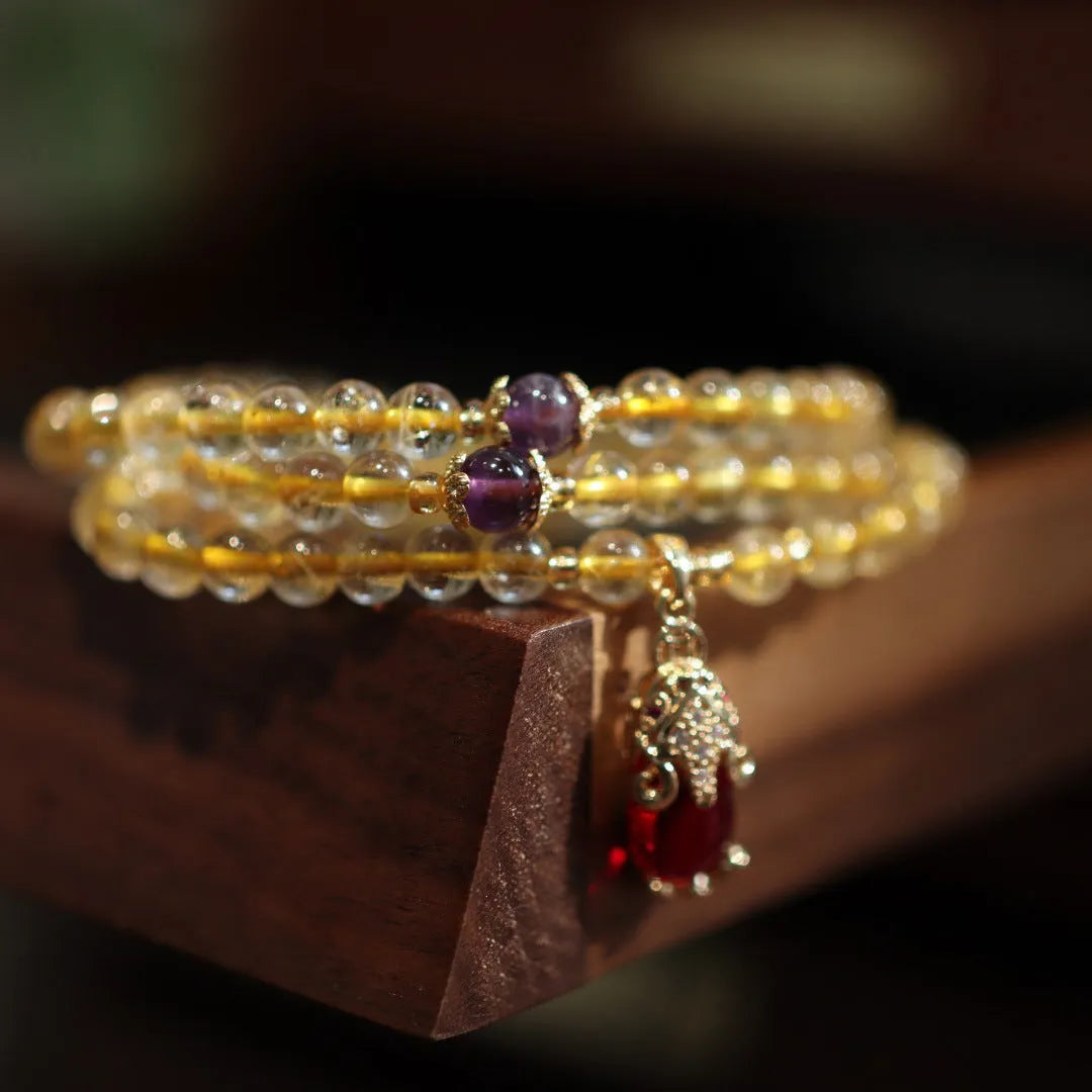 Handmade gold rutilated quartz bracelet with three-circle Chinese design and hanging chopsticks.