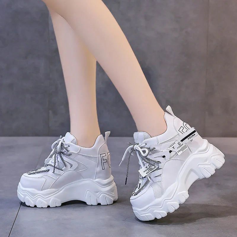 White and black women's low-top platform sports shoes with a cross strap and mesh upper.