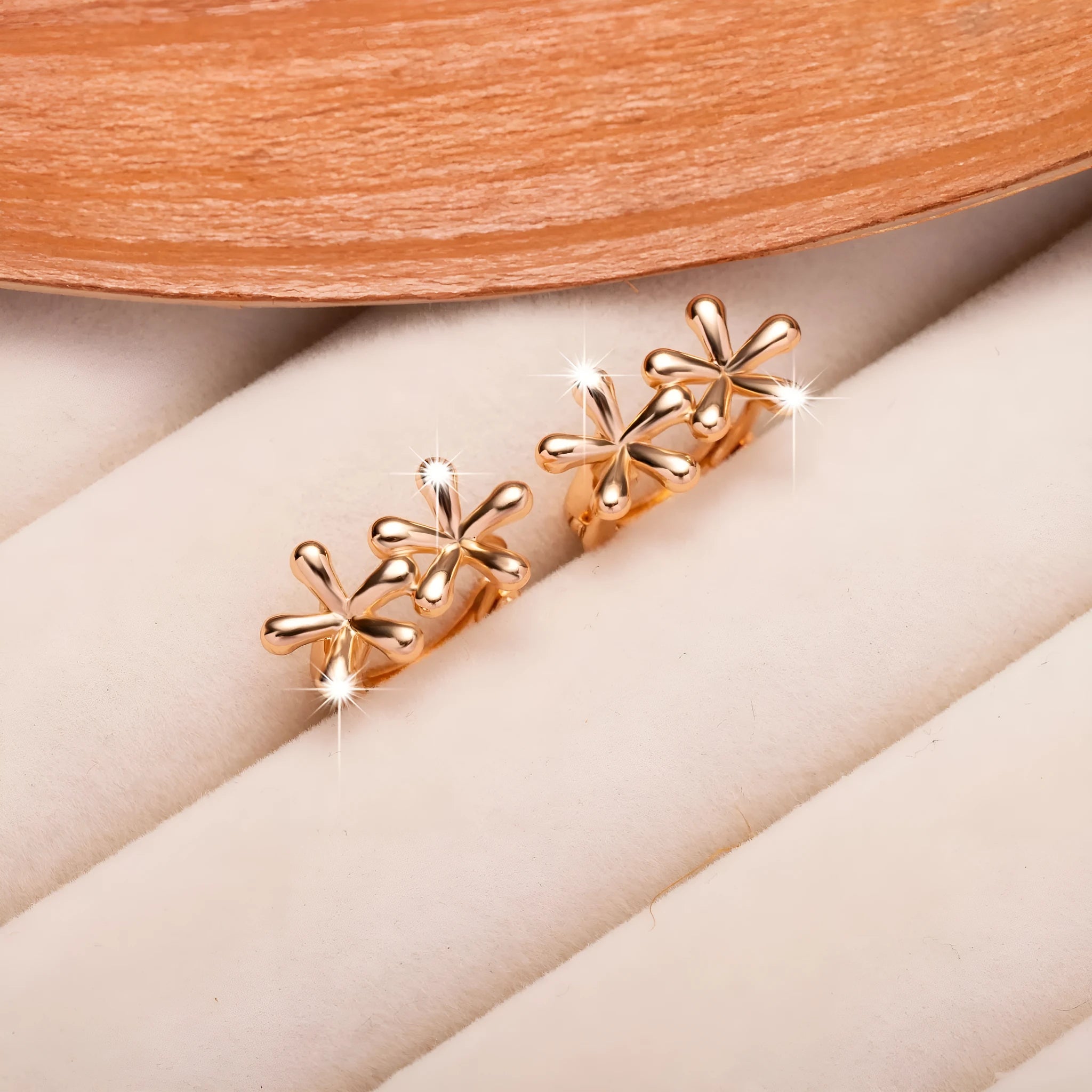 Rose gold circular earrings with a waterdrop flower design on a white background.