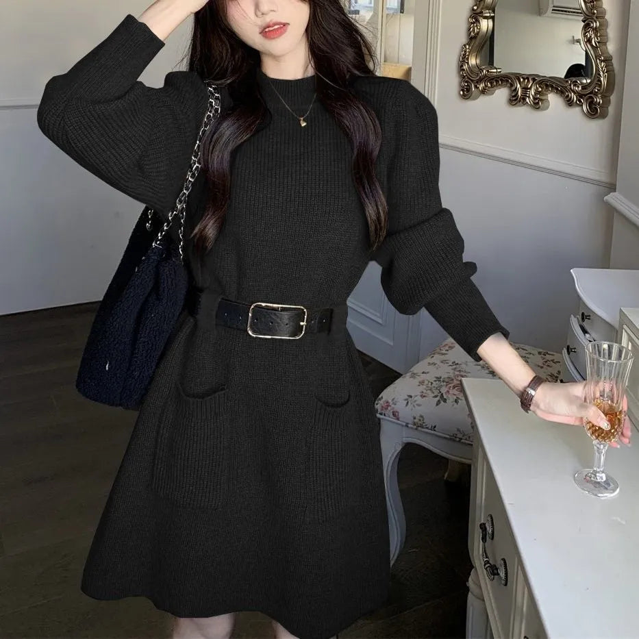 Long sleeve high-waist knitted dress on a hanger with a black belt, shown in beige colour.