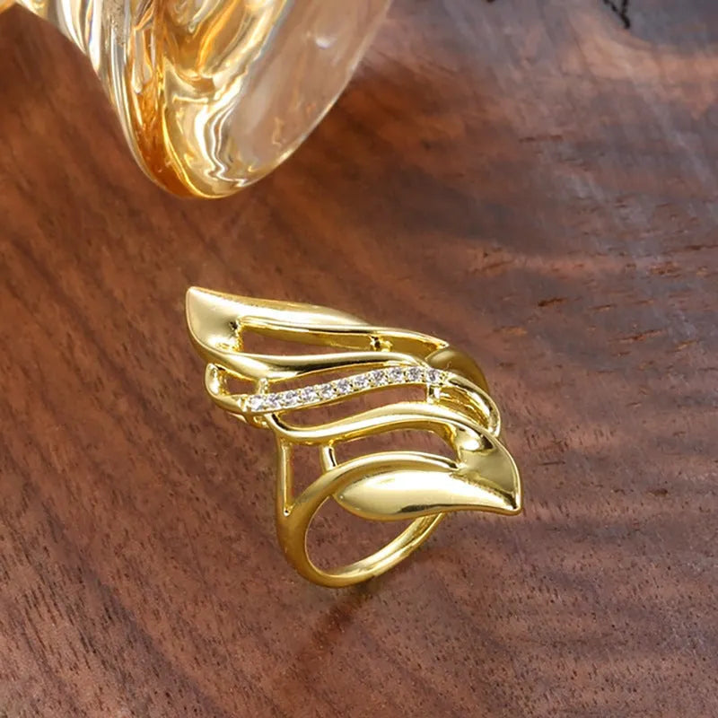 Gold-colour women's ring with exaggerated curved design and zircon crystal detail on a copper band.