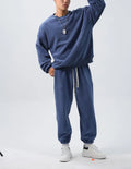 Man wearing a black polar fleece sports suit with a crew neck coat and loose trousers.
