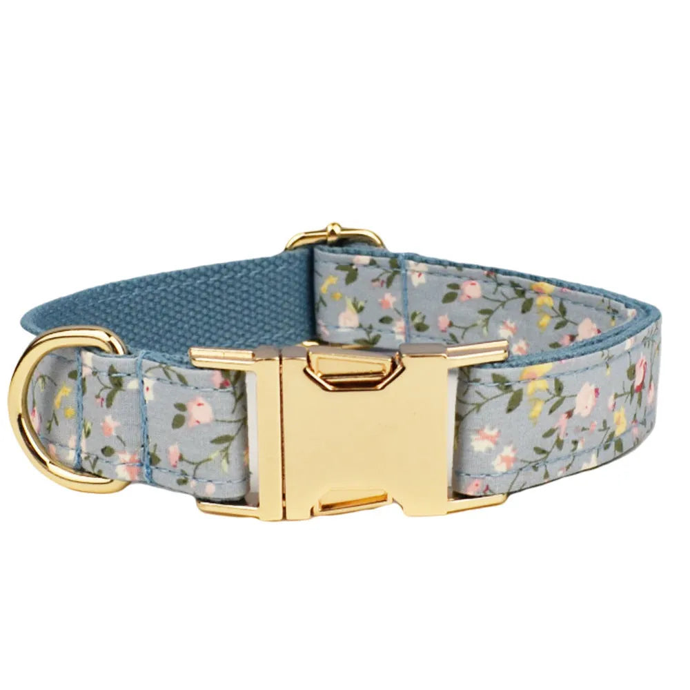 Blue floral patterned dog collar and matching leash, bow, vest, and poop bag set on a white background.