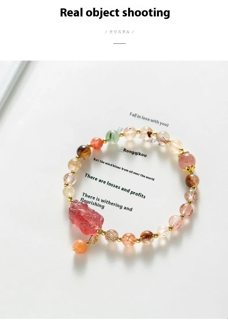 Copper women's bracelet with a pink Strawberry Quartz crystal and a gold-toned Pixiu charm, alongside smaller crystal beads.