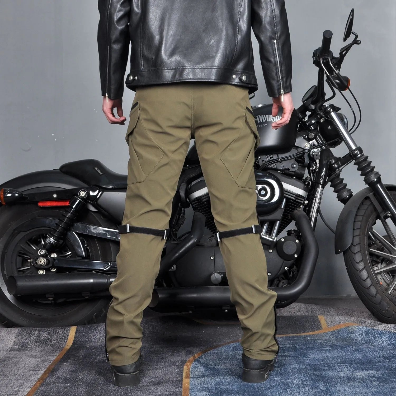 Men's solid green waterproof motorcycle cycling pants laid flat, showing belt and protective gear set.
