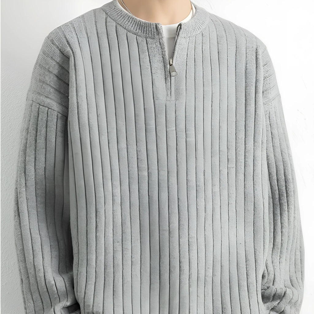 Man wearing a grey textured knit half-zip sweater with a loose fit and long sleeves.