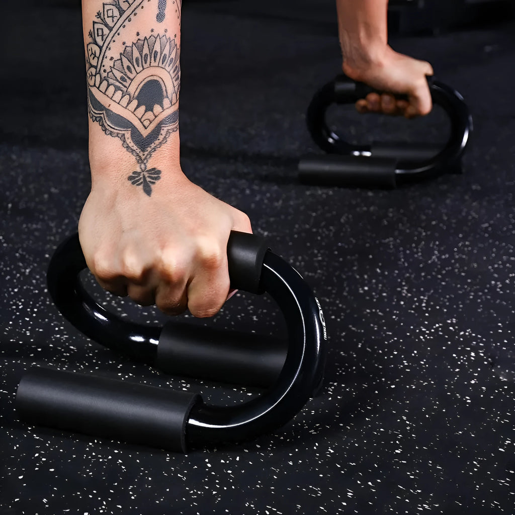 Black S shape push-up bracket rack on a home gym floor