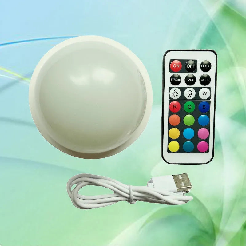 Colourful gradient 3D shooting light night light with remote control on a surface.