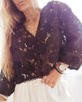Black loose V-neck cardigan with white three-dimensional lace flowers on the front and hollow long sleeves.