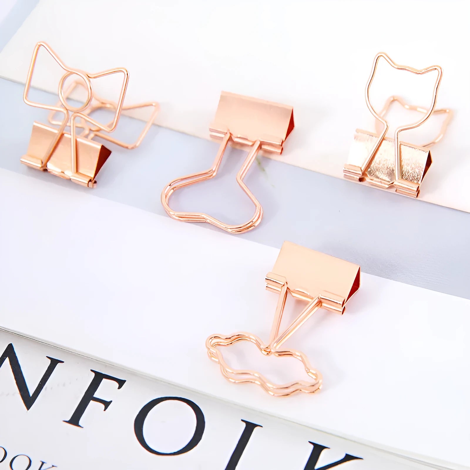 Gold metal decorative paper clips in shapes of a flamingo, a cat, a cactus, a bow, a love symbol, and clouds.
