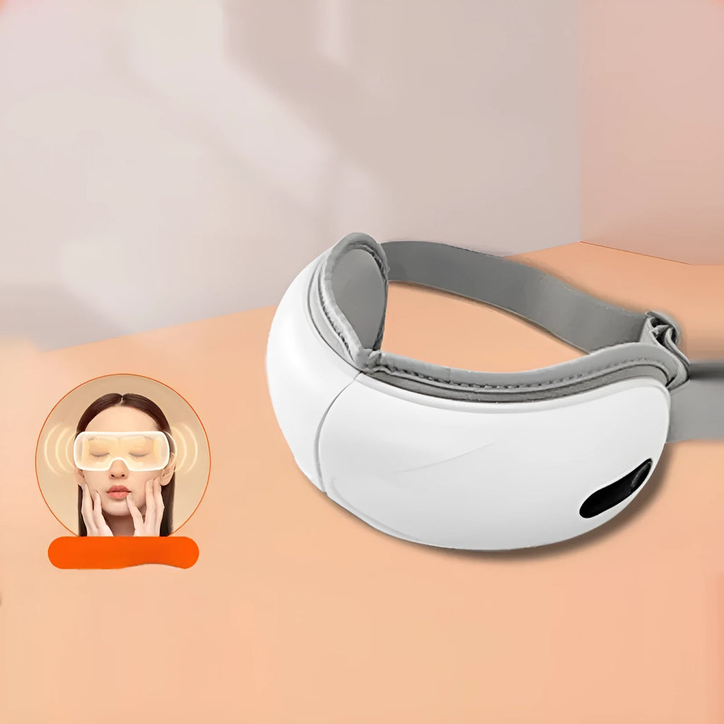 White rechargeable eye massager with hot compress and airbag massage functions on a table.