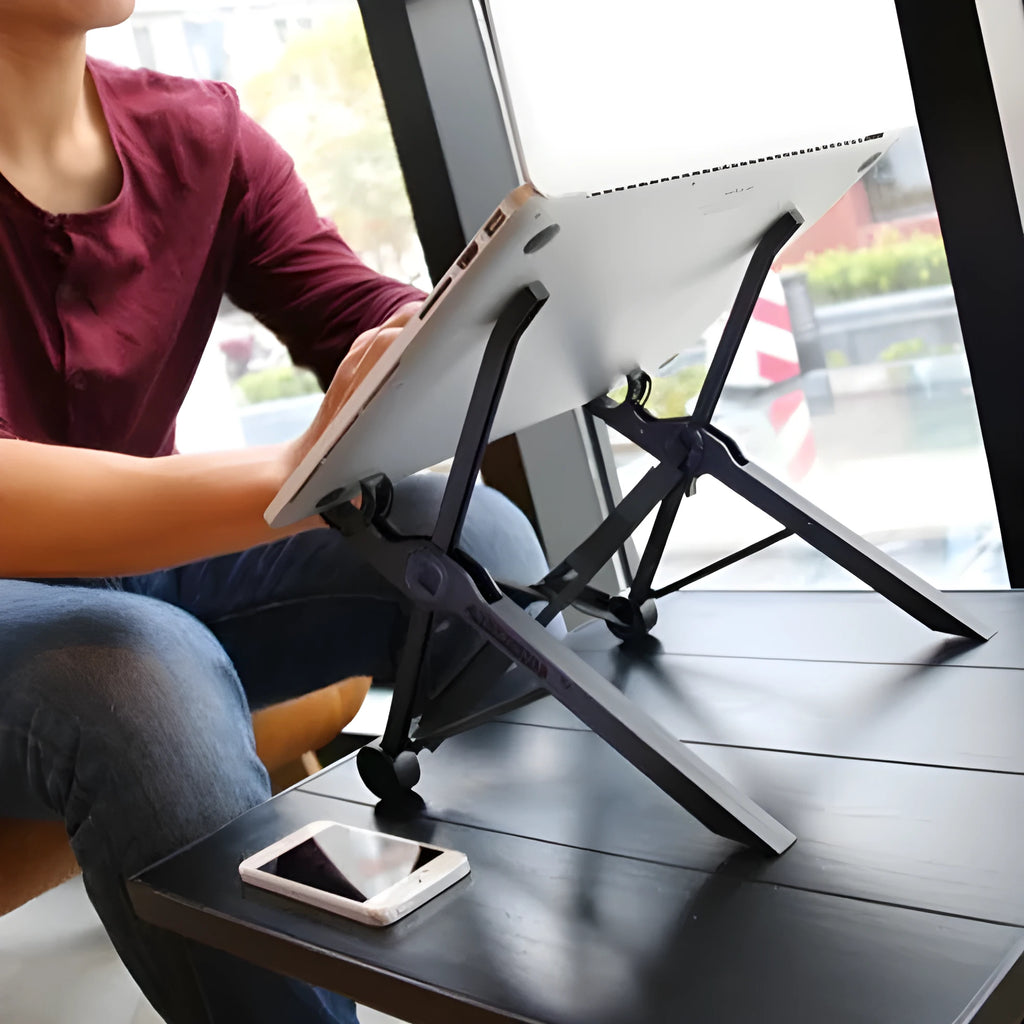 Sagacious black portable folding laptop stand bracket on a desk next to a laptop.
