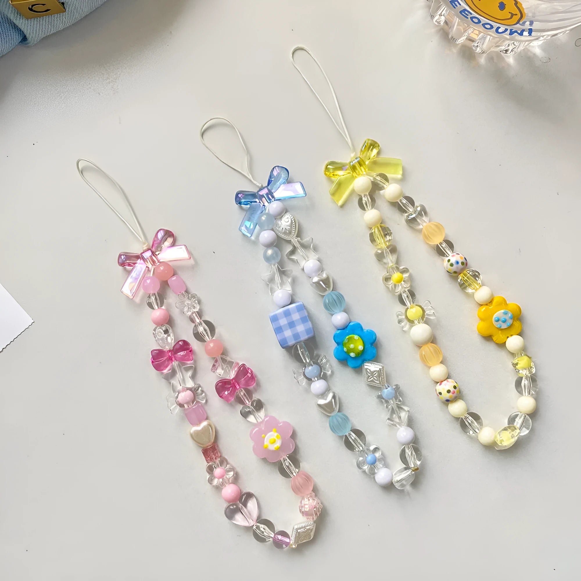 Blue, pink, and yellow beaded flower phone lanyard on a white background.