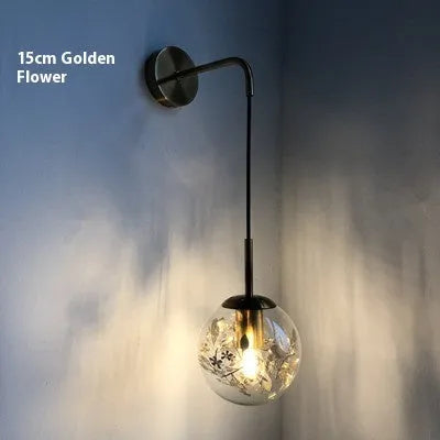 Modern glass wall lamp with golden flower finish and warm white LED light.