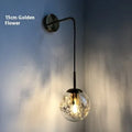 Modern glass wall lamp with golden flower finish and warm white LED light.