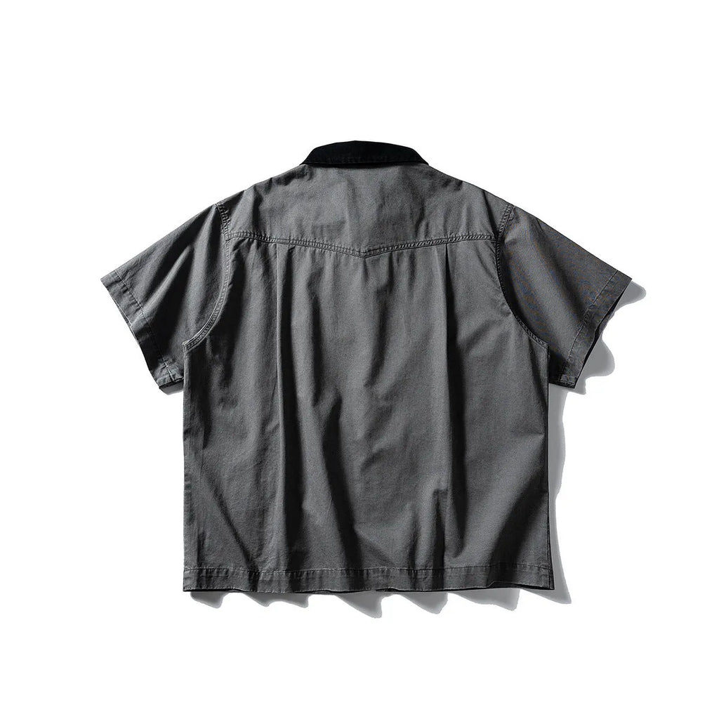 A loose grey or khaki cotton short-sleeved overall shirt, shown as an oversized cardigan style.