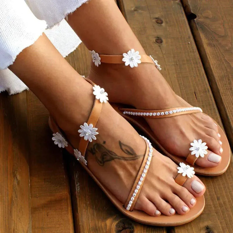 Brown women's flat Roman sandals with floral decoration and herringbone toe.