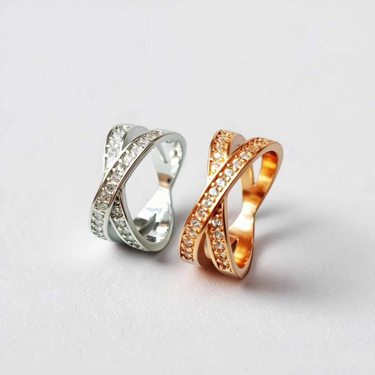 A silver geometric cross ring with micro-inlaid zircon stones on a finger, showing side profile.
