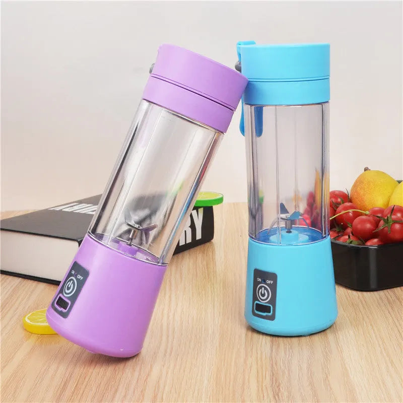 Pink mini USB electric centrifugal fruit juicer with stainless steel blade on a table.