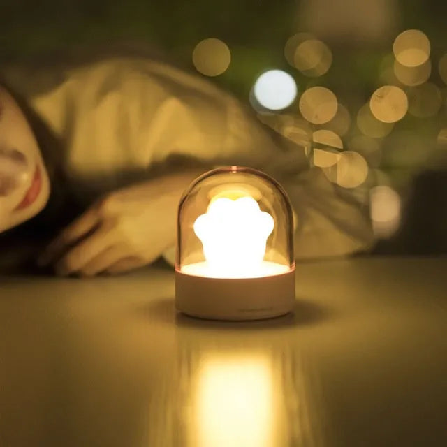 Cute grey or pink cat paw shaped USB rechargeable night light with music box on a desk.