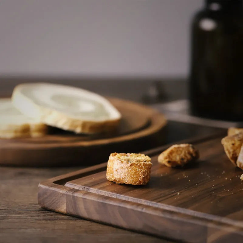 Solid black walnut wood chopping board with a deep perimeter groove and a side handle, shown as a serving tray.