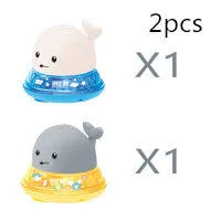 White and blue electric whale bath toy spraying water with flashing lights on a bathroom surface.